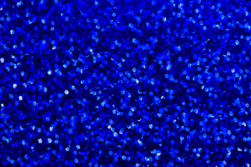 Background with navy blue sequin texture. Glitter background for Holiday and party banner. Abstract glitter poster with blinking lights. Fabric sequins in bright colors.