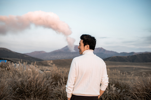 Lonely man in Area of Aso active volcano background with smoke at Mount Aso Nakadake, Kumamoto, kyushu, Japan.
(Photo grain some noise on film colour)