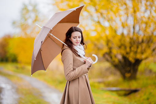 Attractive young elegant girl walking in the park with umbrella, autumn day, copyspace