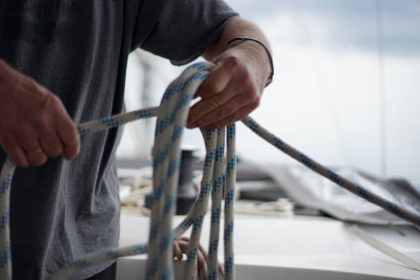 Close up of hands of a man coiling up a rope, the sheet on a sailboat stock photo
