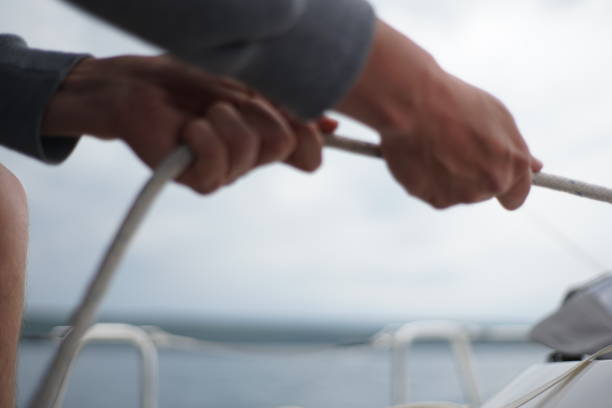 istock Close up of hands pulling a rope, sheet on a sailboat 1203923237