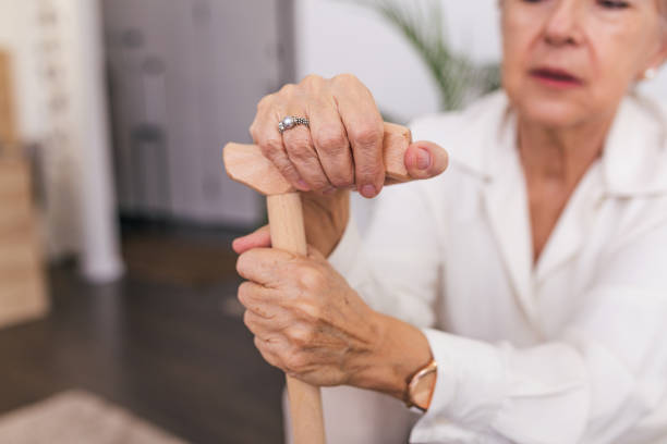 杖を持つ老婦人の手、木製の歩行棒でソファに座っている老婦人。老人ホームでサケを持つ先輩女性のクロップドショット - human hand aging process senior adult cane ストックフォトと画像