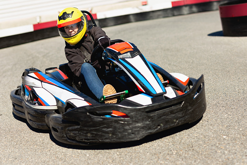 Glad positive smiling woman driving sport car for karting  in a circuit lap outdoor in sport club