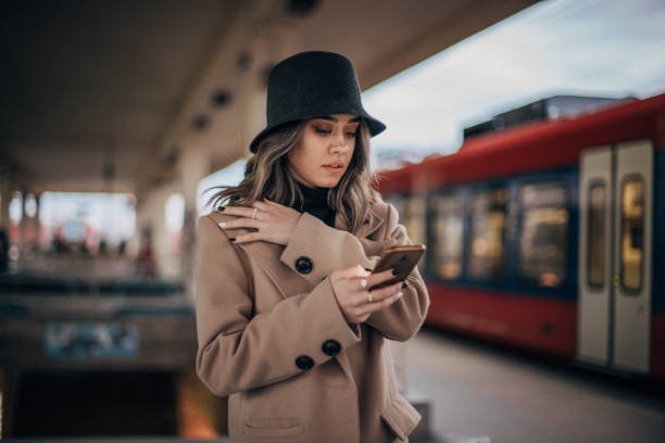 istock Young woman using mobile phone on the train station 1203924667