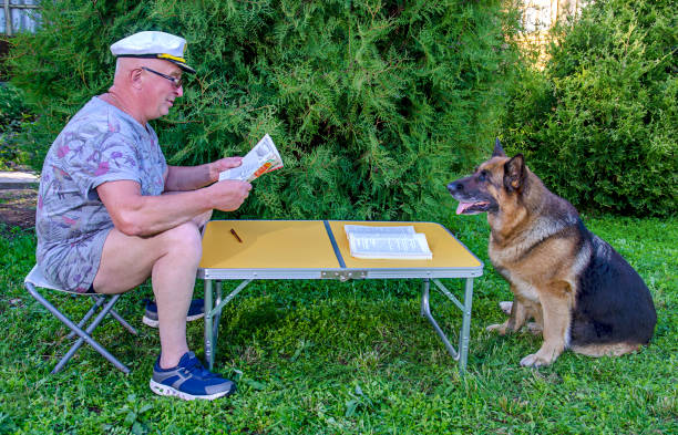 hombre revista perro lee - newspaper dog pets grass fotografías e imágenes de stock