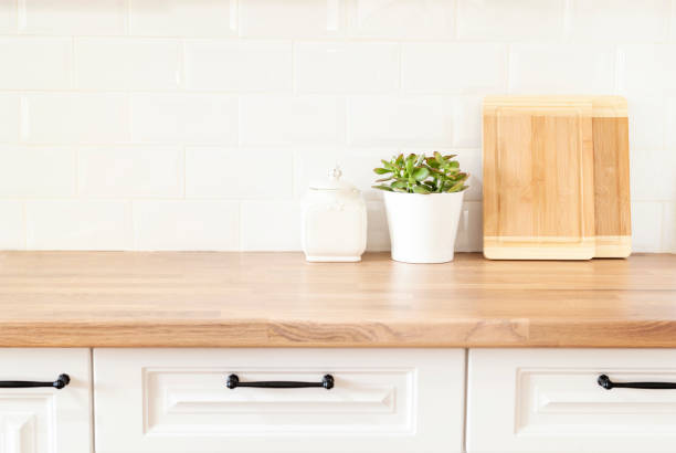 Bright And Clean Kitchen With White Cabinets, Close Up. Cutting Boards, Green Succulent Pot On A Wooden Worktop. Kitchenware In Modern Kitchen Interior. White Tiles Background