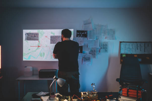istock Man terrorist observing a city map in dark workshop 1203927300