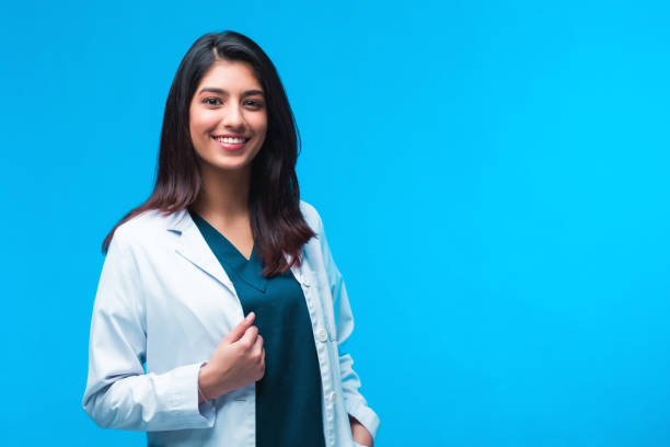 Medical concept of Asian beautiful female doctor in white coat with stethoscope, waist up. Medical student. Woman hospital worker looking at camera and smiling, studio, blue background Medical concept of Indian beautiful female doctor in white coat with stethoscope, waist up. Medical student. Woman hospital worker looking at camera and smiling, studio, blue background admiration photos stock pictures, royalty-free photos & images