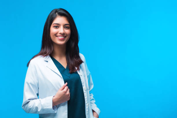 medical concept of asian beautiful female doctor in white coat with stethoscope, waist up. medical student. woman hospital worker looking at camera and smiling, studio, blue background - doctor stethoscope nurse asian ethnicity imagens e fotografias de stock