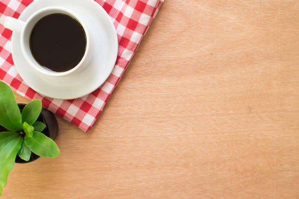 Coffee, cloth red plaid and tree pot on rustic brown wooden desk. top view.