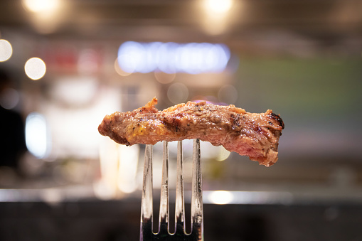 Medium grilled strip loin beef steak. Beef steak on fork.