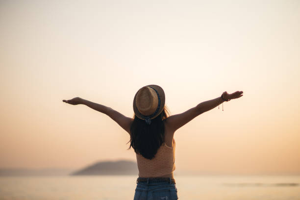 istock Woman watching sunset at beach 1203931453