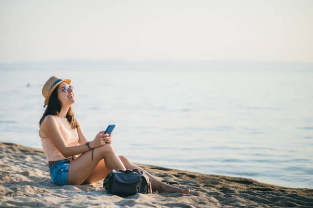 istock Woman at the beach texting on smartphone 1203931554