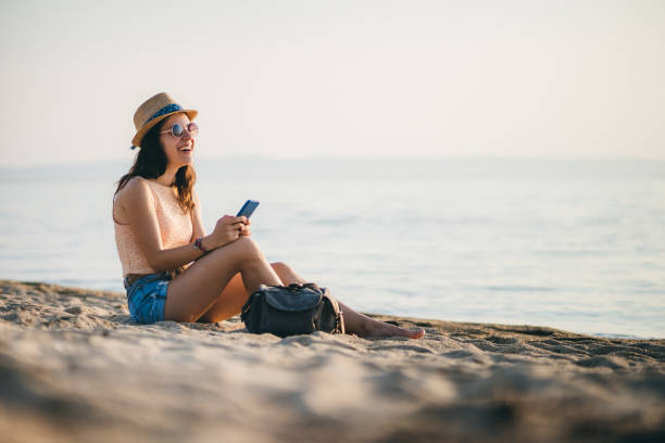istock Woman at the beach texting on smartphone 1203931593