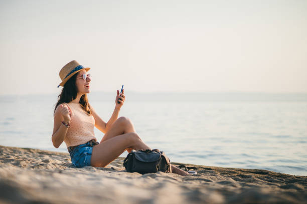 istock Woman at the beach texting on smartphone 1203931616