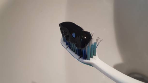 istock Black tooth paste with active charcoal, and black tooth brush on white background 1203932532