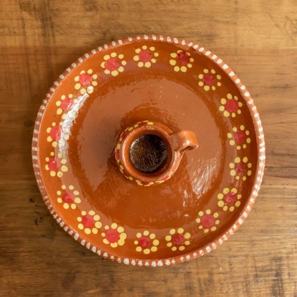 Miniature traditional mexican jar handmade craft Miniature jar and traditional clay mexican plate hand painted with floral pattern flowers on an old wooden surface against a blurry rocky background in a kitchen spanish flower pots stock pictures, royalty-free photos & images