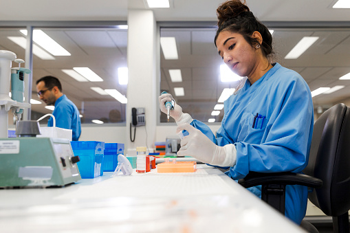 A female medical Scientist working in the Genome Centre laboratory for the Institute for Immunology and Infectious Disease at Murdoch University, Perth, Australia. A male co-worker can be seen in the background.