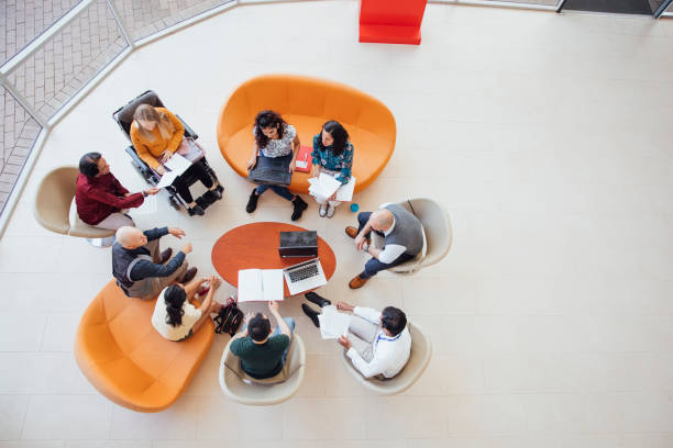 Diverse Group Discussion A birds-eye view of an academic group meeting in natural light with bright furniture. office interior in vibrant stock pictures, royalty-free photos & images