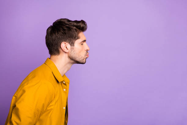 Side profile photo of serious man kissing empty space sending it to his beloved one with eyes closed isolated pastel color violet background Side profile photo of serious man kissing empty space sending it to his beloved one with eyes closed isolated pastel color, violet background mouths kissing stock pictures, royalty-free photos & images