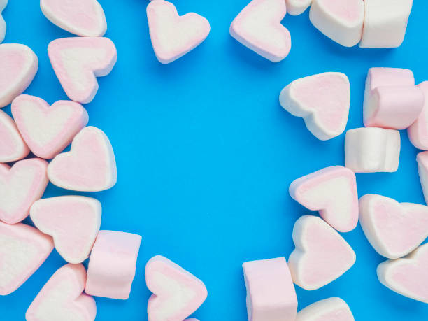 istock Pink marshmallow in heart shape stacked on trendy blue background with copy space. Sweet candy for love theme on Valentine concept. Pastel color dessert for background or wallpaper decor 1203940809