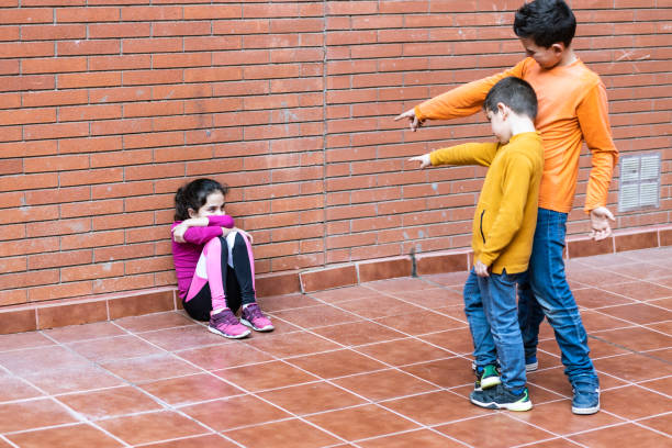 due ragazzi che fanno bullismo a una ragazza - bullying sneering rejection child foto e immagini stock