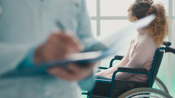 Doctor writing medical records and patient in a wheelchair stock photo