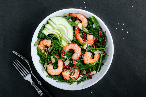 Shrimp salad with fresh green arugula leaves and avocado, radicchio, almond and sesame seeds. Healthy lunch bowl salad.