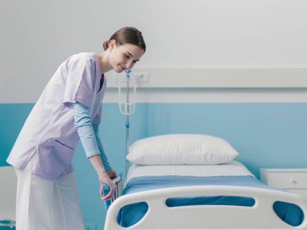istock Young trainee nurse working at the hospital and adjusting bed rails 1203942777