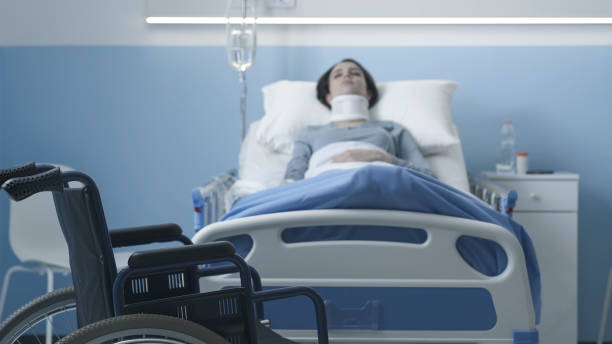 Young woman hospitalized after a serious accident Young woman lying in a hospital bed after a serious accident, wheelchair in the foreground paraplegic stock pictures, royalty-free photos & images