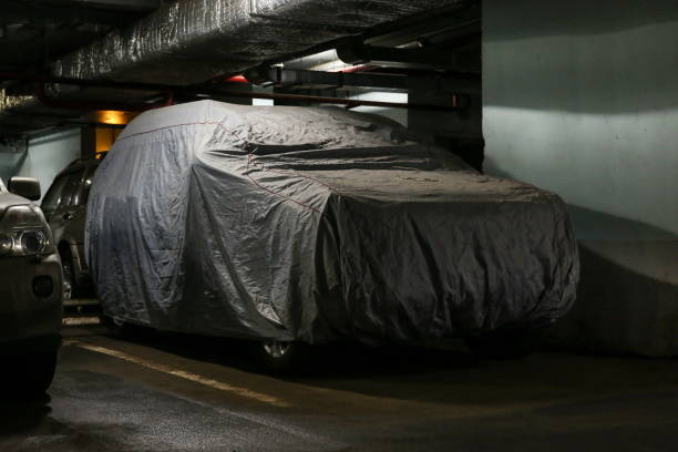 istock covered car in a dark underground parking. suv under protective cover on parking 1203944062