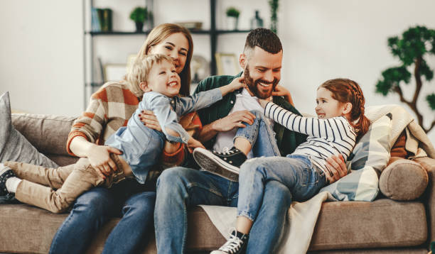 felice famiglia madre padre e figli a casa sul divano - family foto e immagini stock