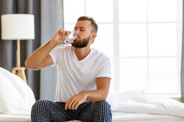 istock young healthy man drinking water in morning 1203947259