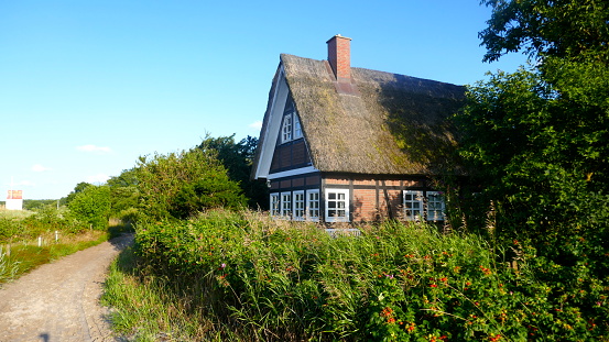 Sehlendorfer Strand / Blekendorf, Schleswig-Holstein, Germany, Europe,  08/08/2019:  
Small cottage with thatched roof between rose hedges very close by the Baltic Sea