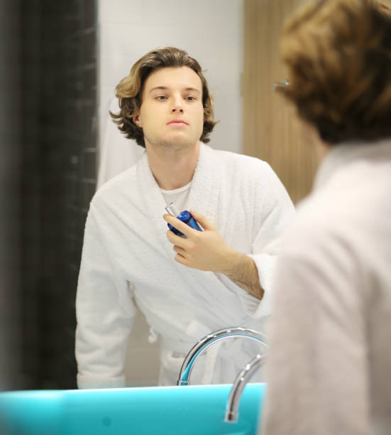 istock young man looking in the mirror,combing his hair,looking at problems on face 1203948128