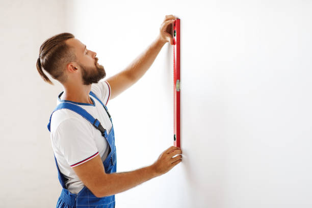 istock male worker makes repairs with level aligns walls 1203952047
