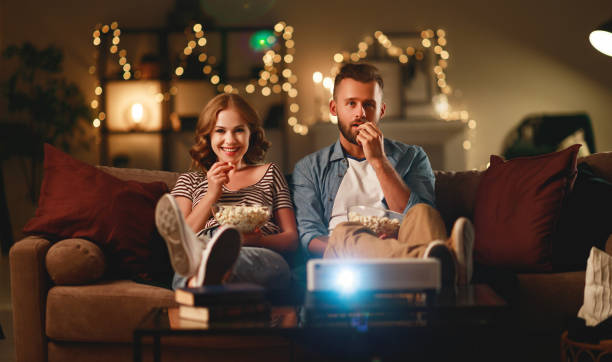 istock Family couple watching television projector at home on sofa 1203954778