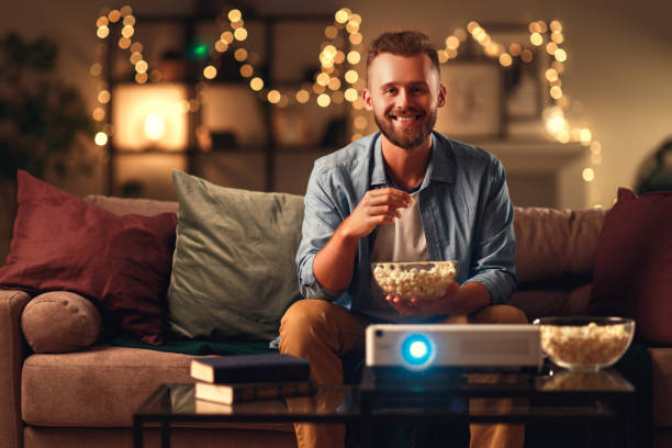 istock young man watching projector tv at home in   evening alone 1203954836