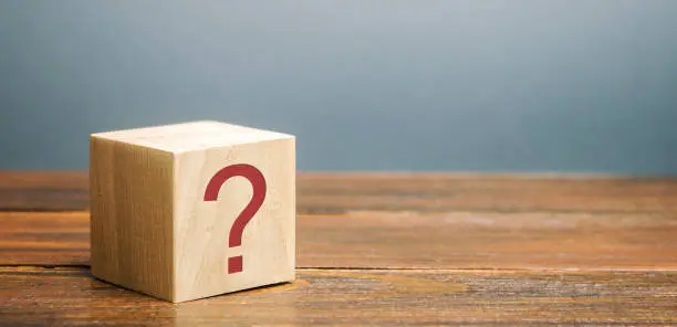 Photo of Wooden block with a question mark. Asking questions, searching for truth. Riddle mystery, investigation and research. FAQ - frequently asked questions. Search for information. Q&A