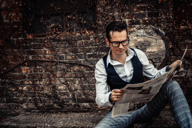 istock Retro-styled man reading newspaper outdoors. 1203957713