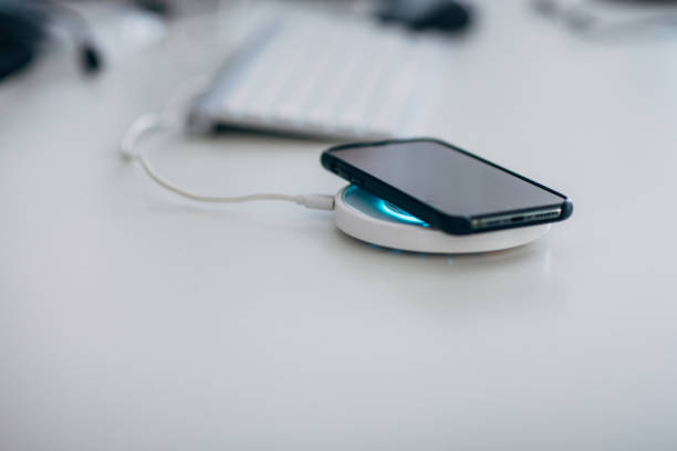 istock Smart phone charging on wireless phone charger next to computer keyboard 1203957831