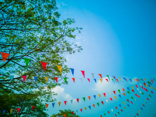 istock Colorful flags, colorful party decorations, small triangular flags to celebrate the party with the blue sky and clouds as the holiday concept background. 1203958175