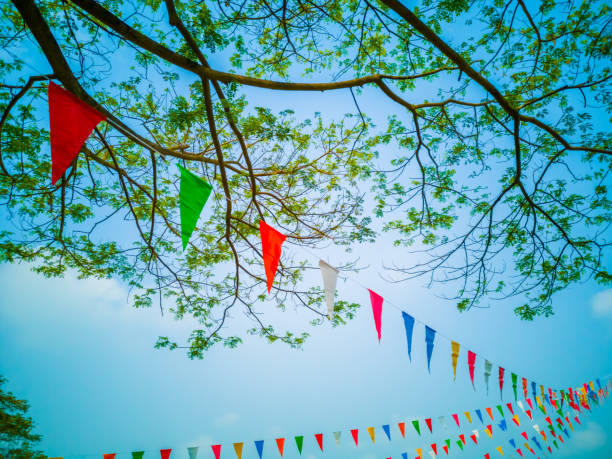 istock Colorful flags, colorful party decorations, small triangular flags to celebrate the party with the blue sky and clouds as the holiday concept background. 1203958250