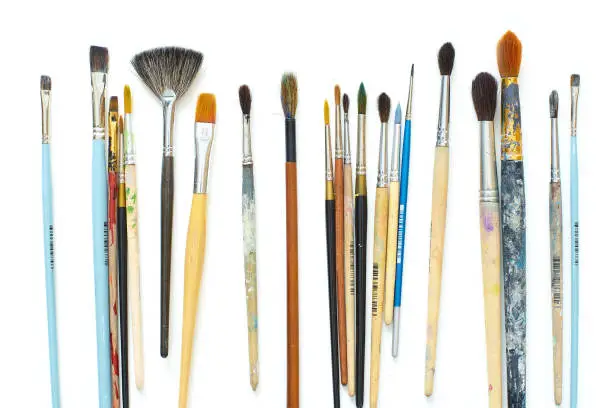 Photo of Used artistic paintbrushes isolated on white background. Close up shot of artist's equipment