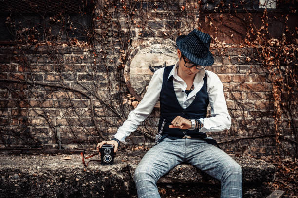 Retro-styled man checking time on wristwatch while sitting outdoors.