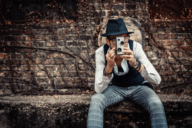 istock Retro styled man filming with old 8mm video camera. 1203960172