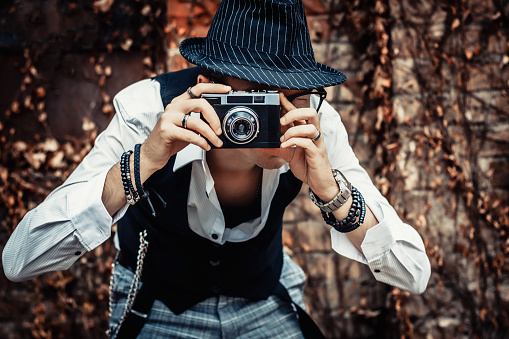 Retro-styled photographer taking picture with analog photo camera.