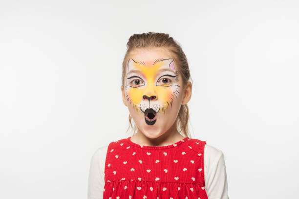 portrait of adorable child with tiger muzzle painting on face looking at camera isolated on white portrait of adorable child with tiger muzzle painting on face looking at camera isolated on white cat face paint stock pictures, royalty-free photos & images