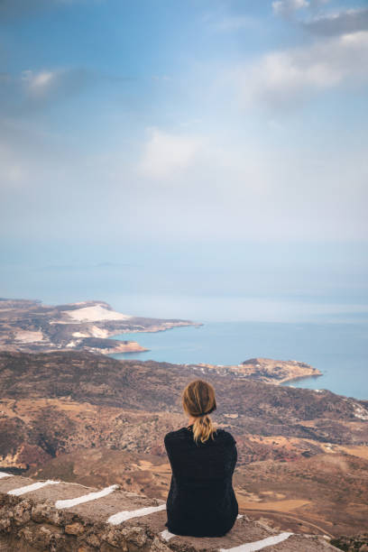 Young woman enjoying the view from the highest point of the island (Profitis Ilias, Milos, Greece).