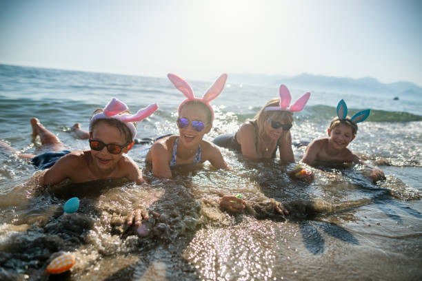 niños y abuelas jugando en el mar durante la pascua de verano - easter easter bunny fun humor fotografías e imágenes de stock